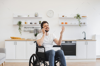 Male with mobility impairment speaking on mobile in kitchen
