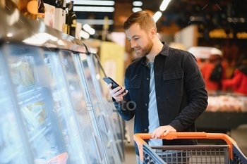 At the Supermarket: Handsome Man Looks at Nutritional Value of the Canned Goods.