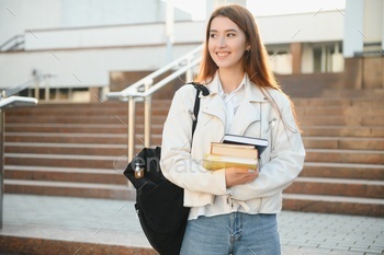 Female college student with books outdoors. Smiling school girl with books