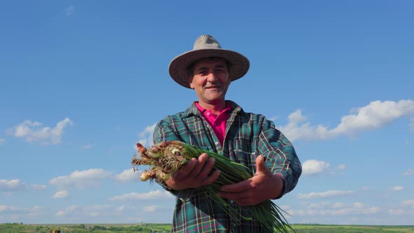 Happy Senior Farmer Looking at Camera are Holding an Armful of Green Onions