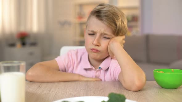 Schoolboy Looking Sadly at Broccoli on White Plate, Childhood Nutrition, Food