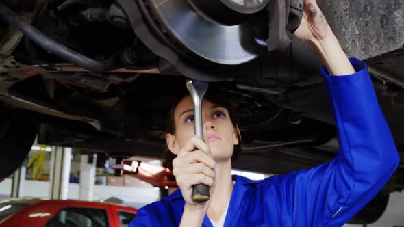 Female mechanic examining car wheel brake disc