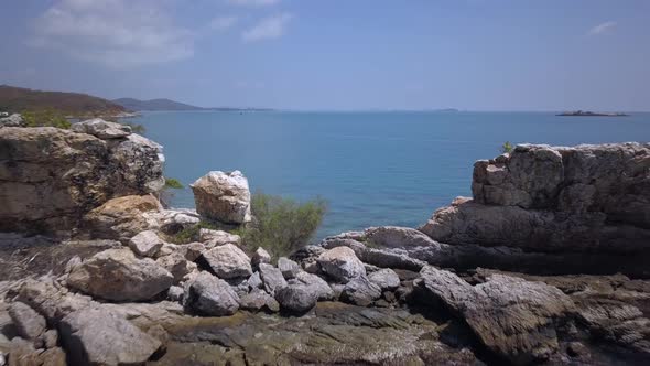 Aerial: a backward low altitude flight revealing an opening between the high rocks and flying slighl