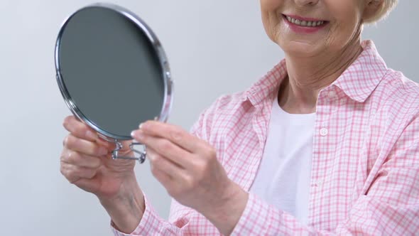 Smiling Elderly Woman Looking in Mirror, Enjoying Appearance, Beauty Care