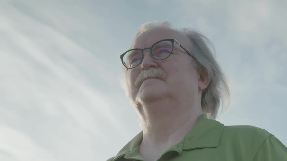 Close up of man with glasses looking out in the distance.