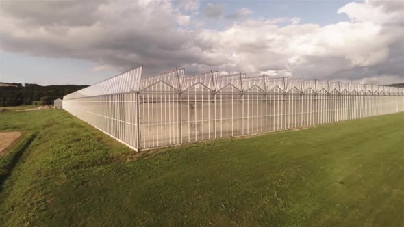 Aerial view of an greenhouse near a field with blu sky on a sunny day. Wide shot.