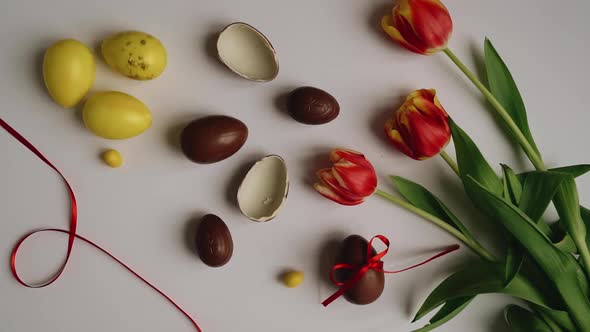 Top shot of Orange tulips flowers on white background with brown and yellow colored easter eggs. Hap
