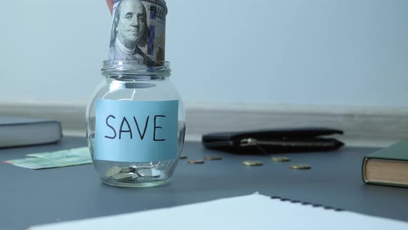 Dollar banknotes in glass jar with coins