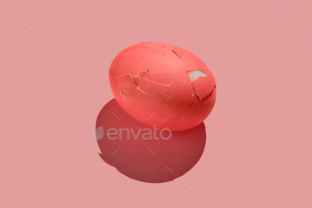 Cracked pink Easter egg on a pink background.