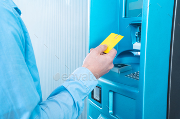 A man is inserting a blue plastic card into the machine