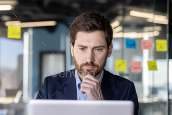 Serious concentrated thinking financier businessman at workplace preparing electronic financial
