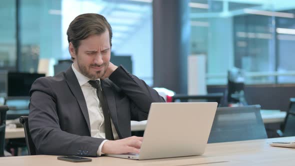 Businessman Having Neck Pain While Using Laptop in Office