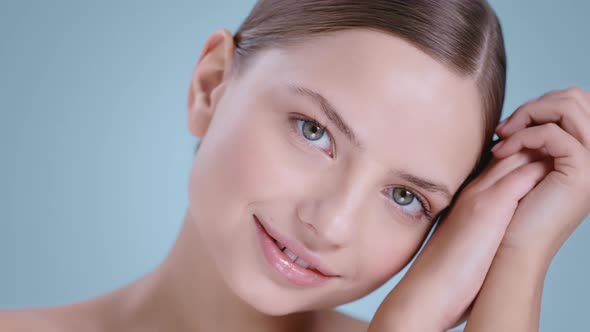 Headshot of Cheerful Young Woman Looking to Camera with Hands Near Her Face 