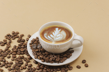 A cup of coffee with coffee art and coffee beans on beige background