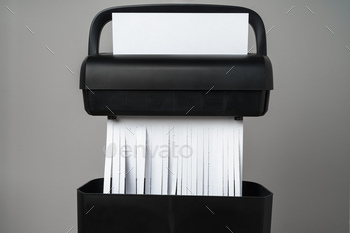 Black paper shredder cutting paper on gray background
