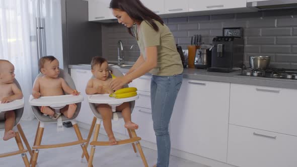 Asian Mom Giving Bananas to Toddler Triplets