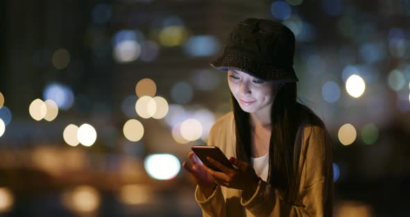 Woman use of smart phone in city at night