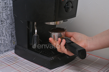 a woman makes coffee on a home coffee maker