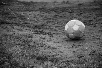 a soccer ball sitting on a field by itself in black and white