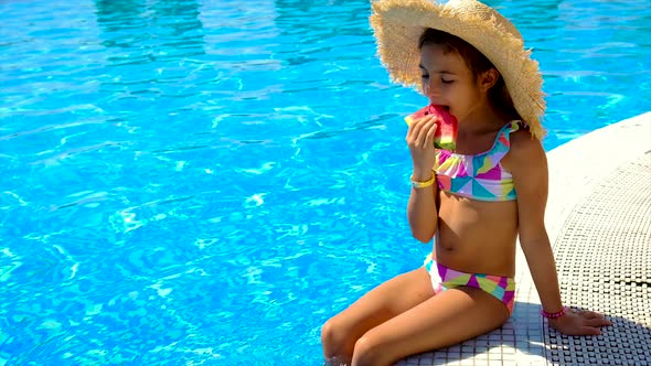 The Child Eats a Watermelon Near the Pool