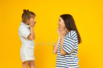 Mother and daughter in amazement, on a yellow background.