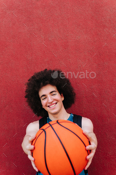 A young man in sports clothing and a basketball on a red background. sport and healthy life