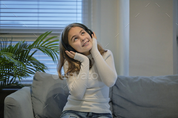 teenager girl with headphones listening to music at home. technology and music concept.