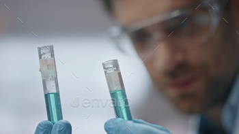 Biotechnology expert checking experiment result in test tubes laboratory closeup