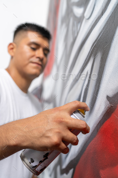 Street artist using spray to paint a wall
