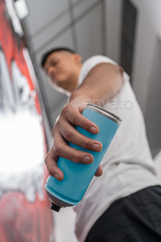 Vandal holding a spray while painting a graffiti on a wall