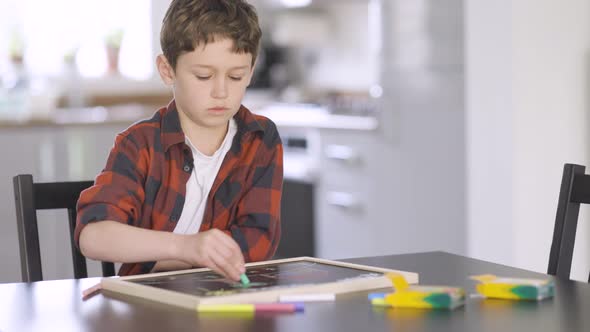 Little boy drawing on blackboard with crayons