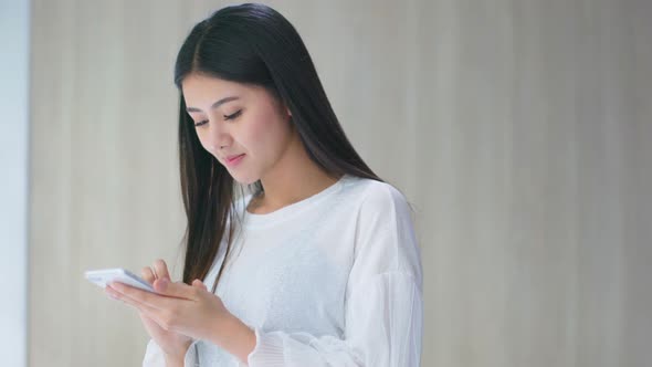 beautiful asian woman enjoy happiness hand use smartphone near window