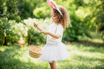 Baby with basket full of colorful eggs. Easter egg hunt.