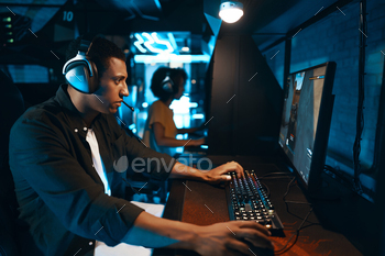 A gamer is using a computer to play video games with headphones on