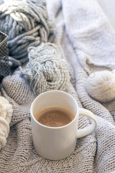 Close-up, cup of coffee, knitted element and yarn threads.