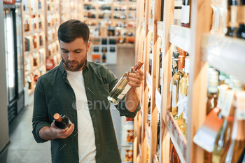 Man is choosing wine in the store