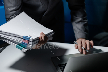 Employee checking important details of document on laptop, Documents were stacked on the desk, A bus