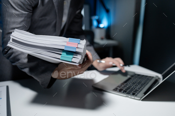 Employee checking important details of document on laptop, Documents were stacked on the desk, A bus