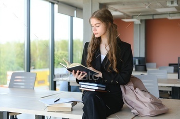 Schoolgirl standing with books and backpack at school.