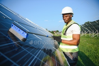 african american worker cleaning solar panel in solar power plant