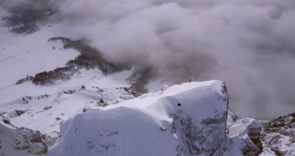 Aerial drone view of a skier skiing down a steep snow covered mountain.