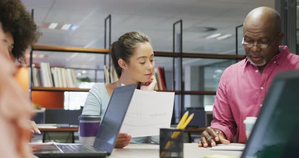 Diverse male and female business colleagues talking and taking notes