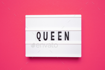 Word QUEEN. White lightbox with letters on pink background.