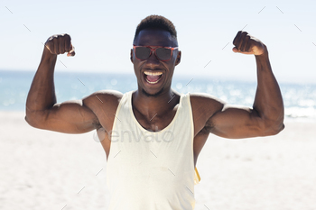 African American man flexes his muscles on the beach unaltered