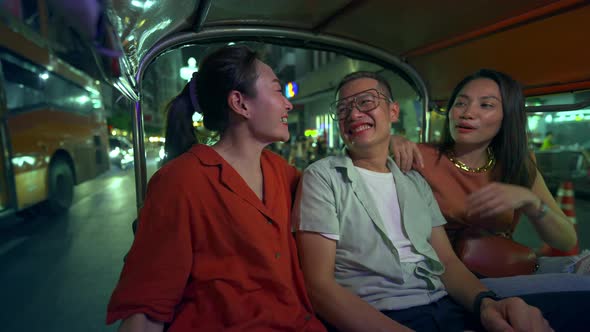 4K Group of Asian people friends traveling in Bangkok city by Tuk Tuk taxi car together at night.