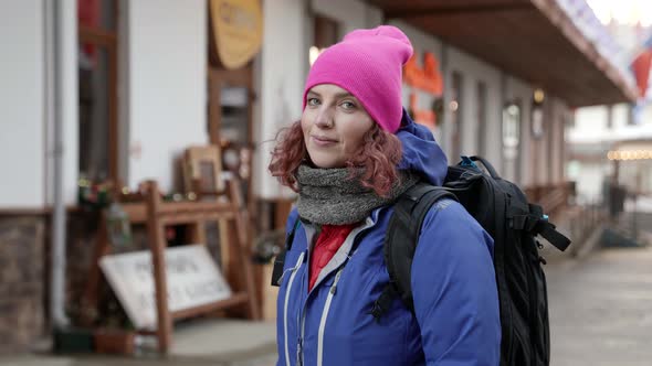 A Woman in a Pink Hat and Blue Jacket Walking and Smiling