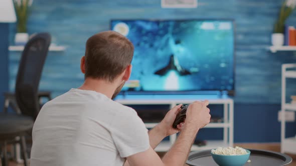 Man Holding Wireless Controller Playing Console Video Game on Tv While Sitting on Sofa