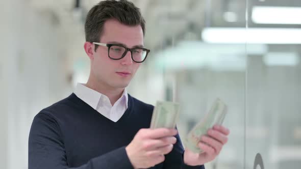 Wealthy Young Businessman Counting Dollars