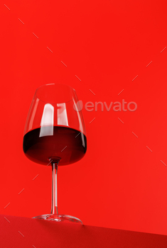Red wine elegance: Wine glass against vibrant red background
