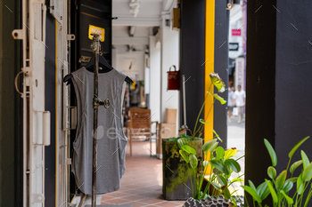 clothing displayed outside of a store with plants and plant pots on the side walk